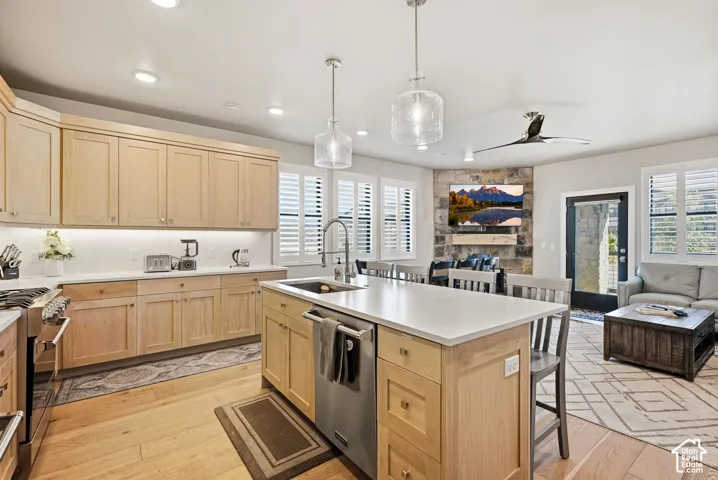 Spacious kitchen featuring light wood cabinetry, white countertops, and a central island with a sink