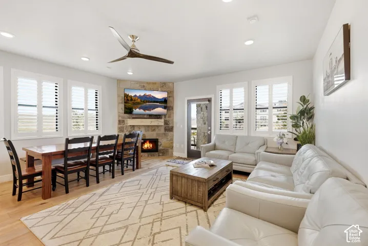 Open-concept living space featuring light wood-finish flooring, recessed lighting, and a stone-clad fireplace