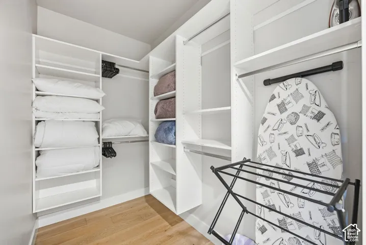 Custom closet system featuring white shelving, hanging rods, and wood-finish flooring