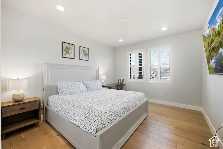 Hardwood-style flooring, recessed lighting, and white plantation shutters