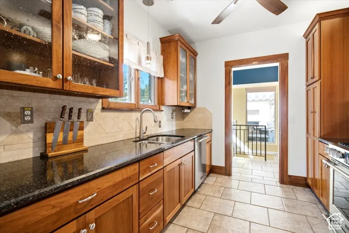 Kitchen featuring wood cabinetry, dark countertops, a tile backsplash, and tile flooring