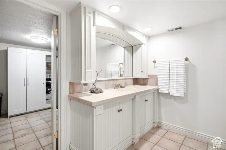 Double vanity with light-toned countertop, beadboard cabinetry, and an arched mirror