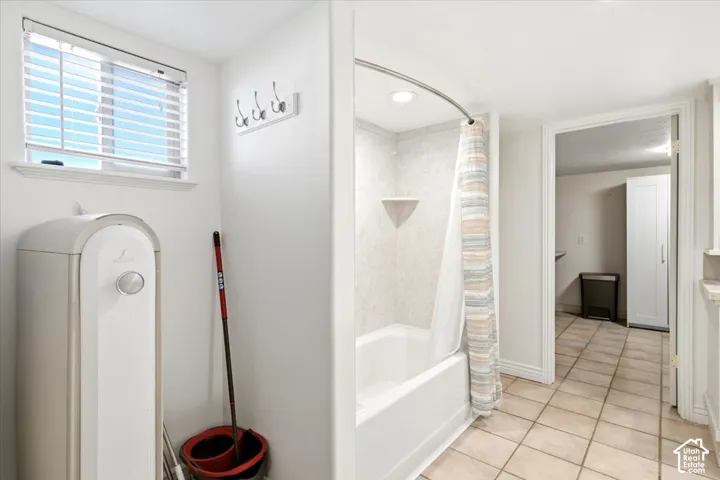 Bathtub with a curved shower rod, tiled shower surround, and built-in corner shelf