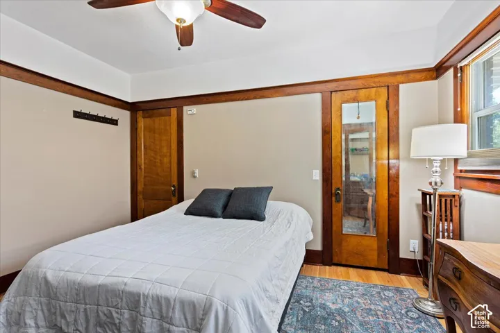 Hardwood flooring, wood-framed windows, wood-paneled door with mirrored insert, and a ceiling fan with integrated lighting