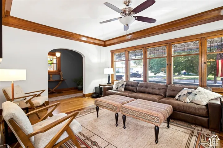 Hardwood flooring, arched doorway, wood-framed windows, stained glass window details, and a ceiling fan
