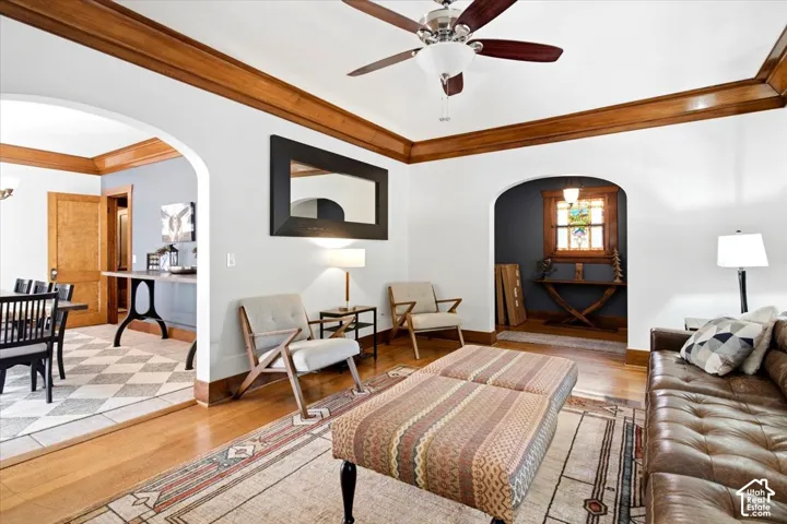 Arched doorways, wood-finish flooring, wood trim details, and a ceiling fan with integrated lighting