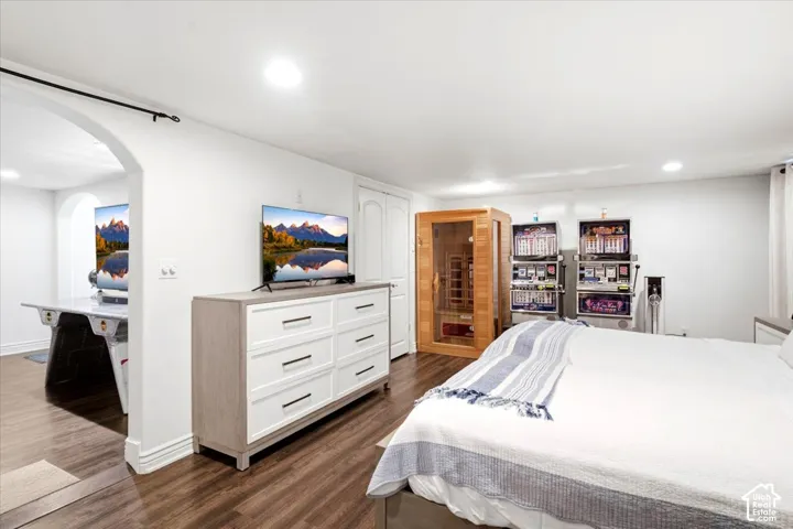 Recessed lighting, wood-finish flooring, white walls, arched doorway, and built-in closet
