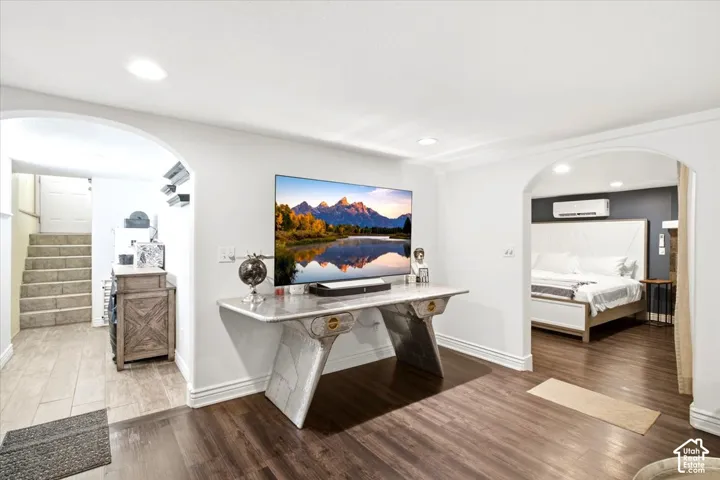 Wood-finish flooring throughout, featuring a recessed lighting, arched doorways, and white baseboards