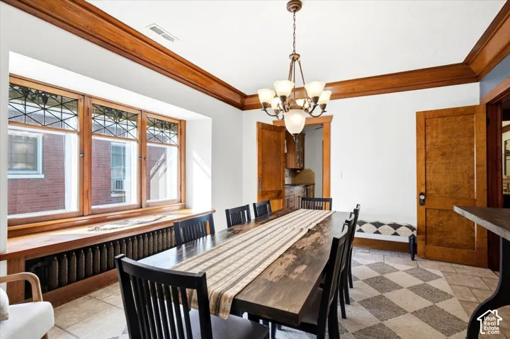 Wood-finish trim and crown molding, coffered ceiling, chandelier lighting, stained glass transom windows, and checkerboard tile flooring
