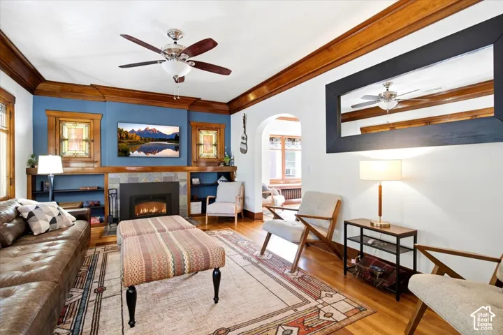 Hardwood flooring, recessed fireplace with tile surround, built-in shelving, stained glass windows, and a ceiling fan with integrated lighting