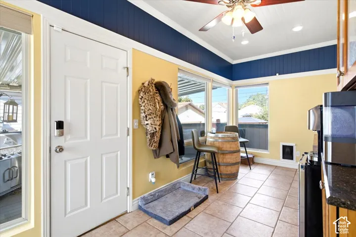 Tile flooring, ceiling fan with light fixture, built-in cabinetry, window-lined wall, and a paneled exterior door