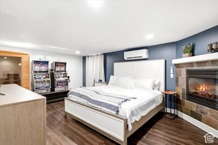 Wood-finish flooring, accent wall, built-in fireplace with stone surround, wall-mounted climate control unit, and recessed lighting