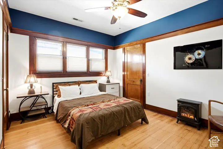 Wood-finish flooring, wood trim throughout, a wood door, multiple windows with blinds, and a ceiling fan with integrated lighting