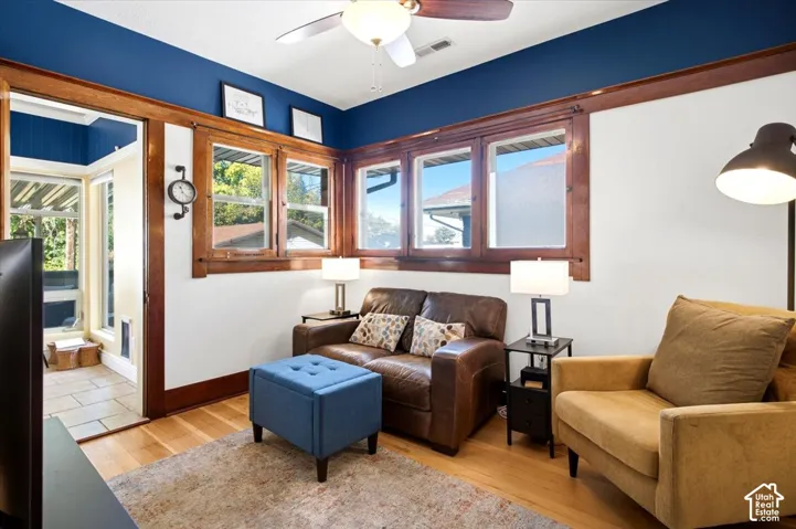 Hardwood flooring, wood trim window casings, painted accent wall, ceiling fan, and tile flooring