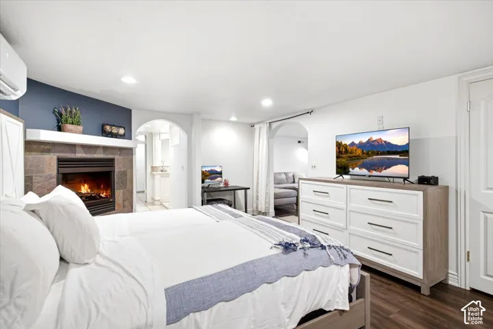 Fireplace with stone surround, wood-finish flooring, recessed lighting, and an arched doorway