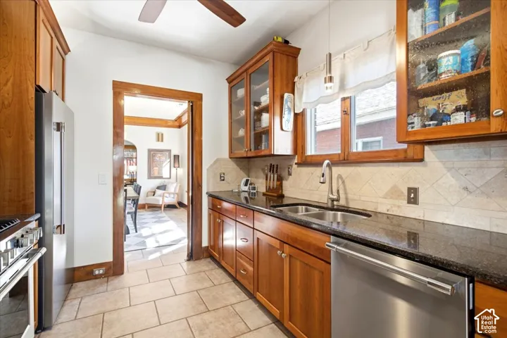 Kitchen featuring wood cabinetry, dark countertops, a tile backsplash, and stainless steel appliances