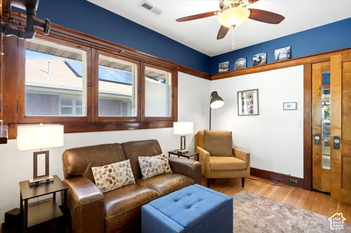 Wood-finish flooring, wood trim detailing, ceiling fan, and built-in sliding pocket doors with glass inserts