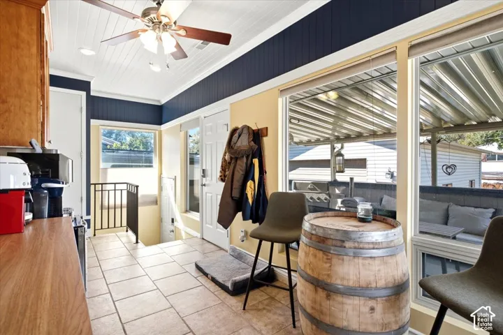Tiled flooring, wood-finish cabinetry, paneled ceiling with ceiling fan, large windows, and outdoor covered patio space