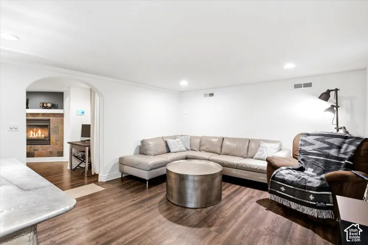 Wood-finish flooring throughout, recessed lighting, and an arched entryway leading to a fireplace with stone surround