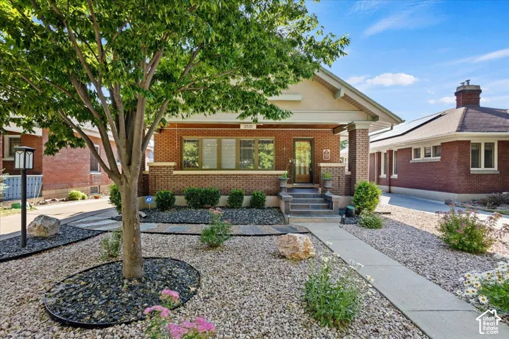 Brick exterior with a covered porch, stone-finish steps, and a decorative front door