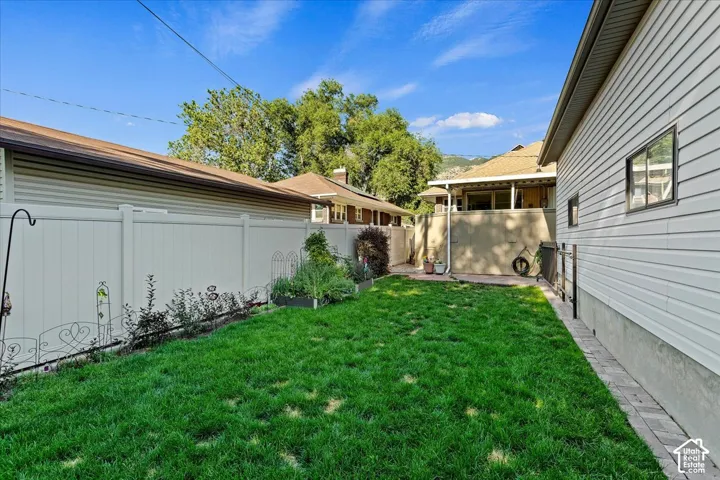 Expansive lawn with a paver border, perimeter planting beds, and a white privacy fence