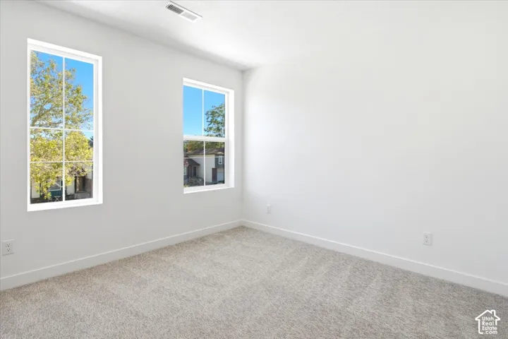 White walls with two vertical windows, light gray carpet, and white trim