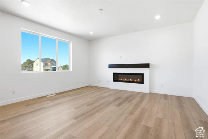 Wood-finish flooring, recessed lighting, and a linear electric fireplace with a dark mantel