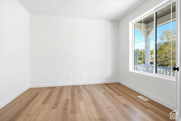 Bright room featuring wood-finish flooring, white walls, and a large window