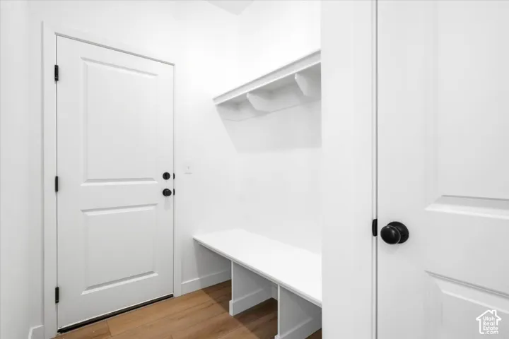 Built-in storage bench with overhead shelving, wood-finish flooring, and white paneled doors with matte black hardware