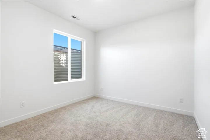 Neutral-toned carpeting, white painted walls, and a white window frame