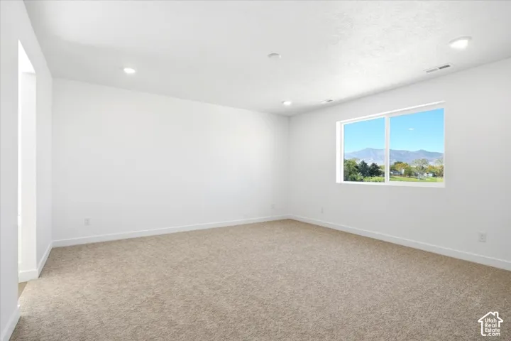Neutral-toned carpeting, white walls, recessed ceiling lighting, and a window with a mountain backdrop