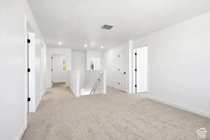 Carpeted landing with white walls, recessed lighting, and white paneled doors with black hardware