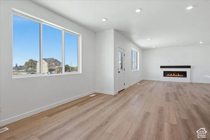 Spacious interior featuring a contemporary fireplace with a dark wood mantel, recessed ceiling lighting, and wood-finish flooring
