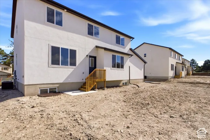 Contemporary stucco exterior with dark trim, multiple windows, and a wood-finish deck with stairs