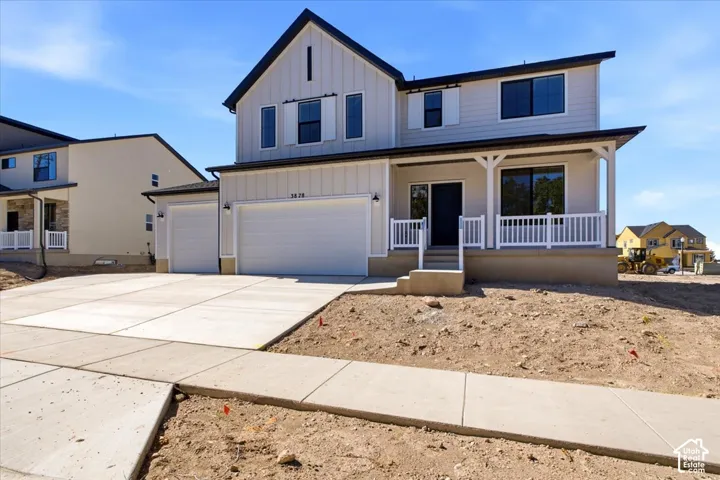 Contemporary exterior with board and batten siding, attached two-car garage, covered porch with white railing, and a concrete driveway