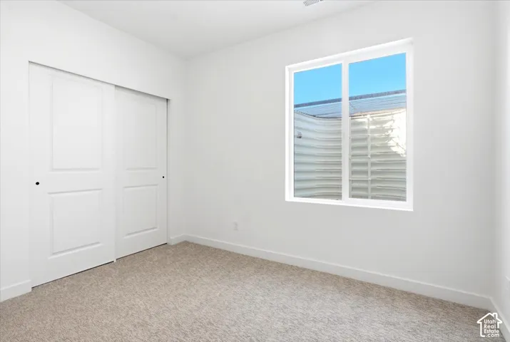 Neutral tone walls, light-colored carpeting, and a window with a white frame
