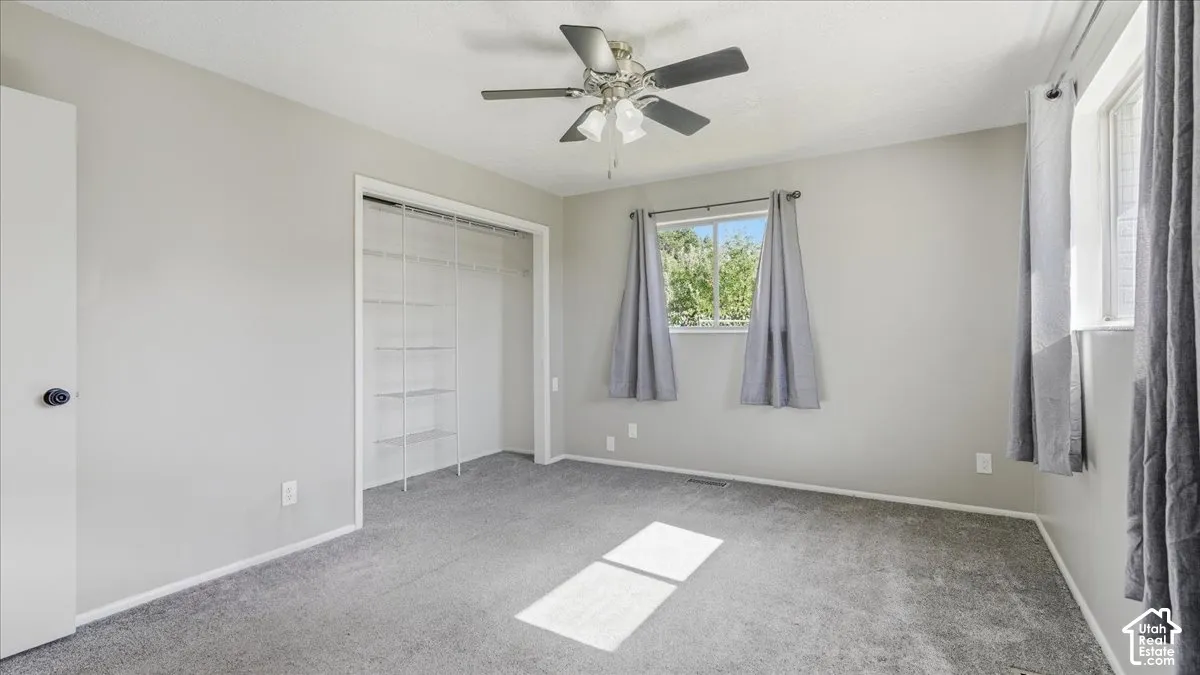 Neutral wall paint, ceiling fan with integrated lighting, two windows, and built-in closet shelving