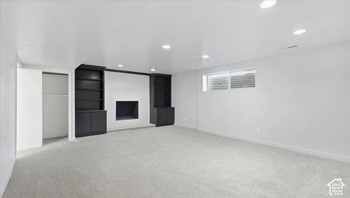 Recessed lighting illuminating a spacious room with light gray carpeting