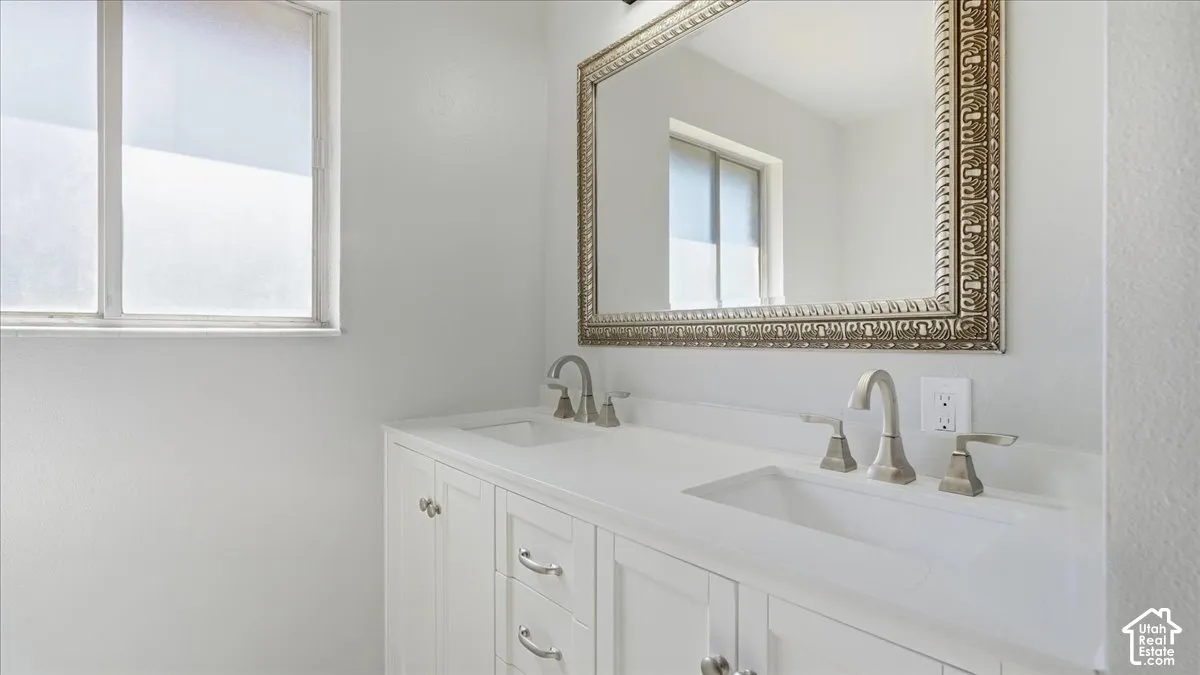 Double vanity with integrated sinks, white cabinetry, and brushed nickel hardware