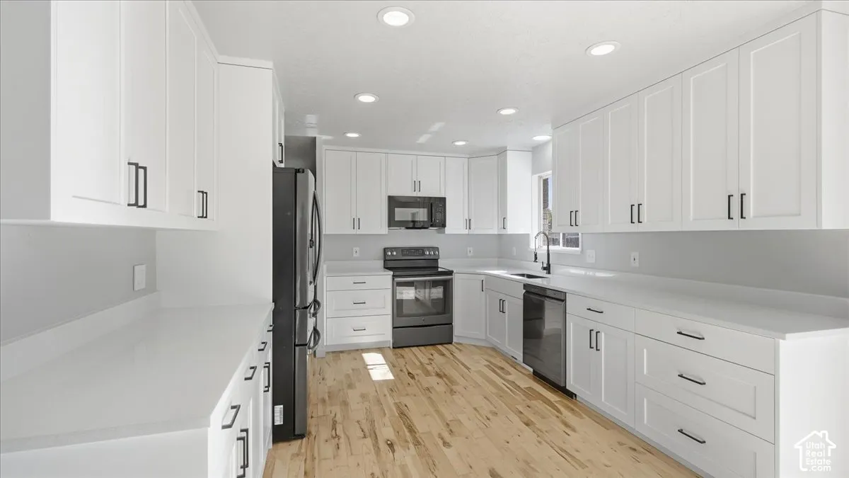 White shaker cabinetry paired with light-toned countertops, wood-finish flooring, and recessed lighting