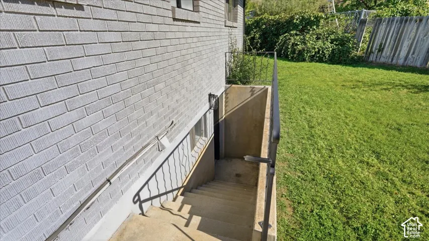 Gray brick exterior with a concrete stairwell, metal handrails, and a window