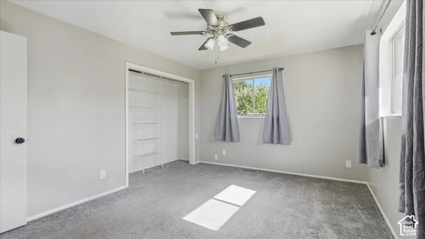 Neutral wall paint, ceiling fan with integrated lighting, two windows, and built-in closet shelving