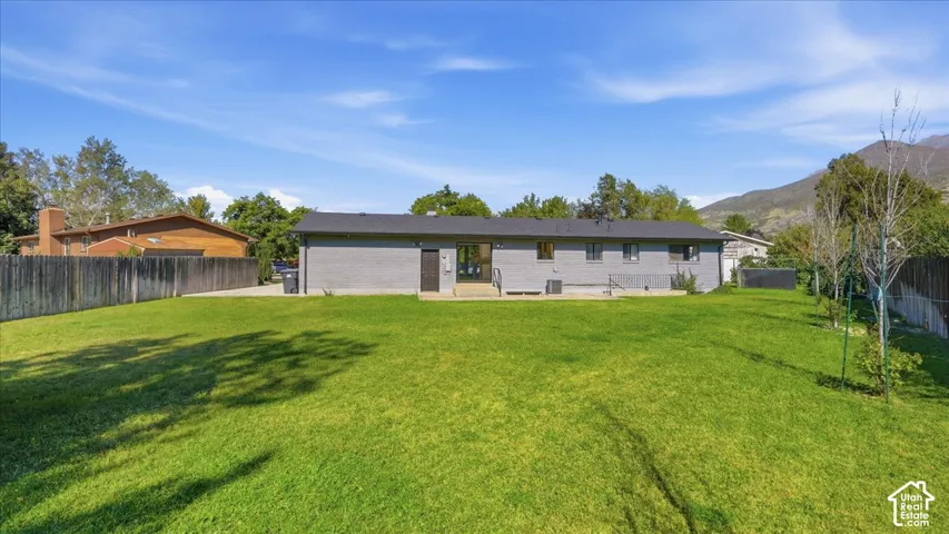 Expansive backyard with a manicured lawn, full fencing, and a mountain backdrop