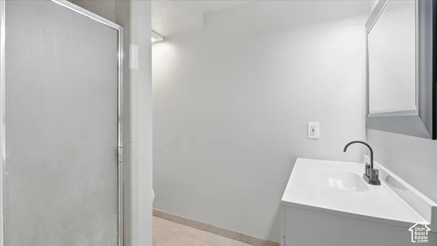 Frosted glass shower enclosure, single vanity with integrated sink, contemporary matte black faucet, and recessed medicine cabinet