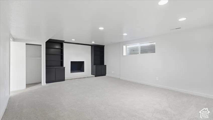 Recessed lighting illuminating a spacious room with light gray carpeting