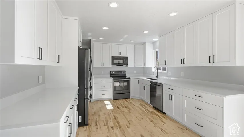 White shaker cabinetry paired with light-toned countertops, wood-finish flooring, and recessed lighting