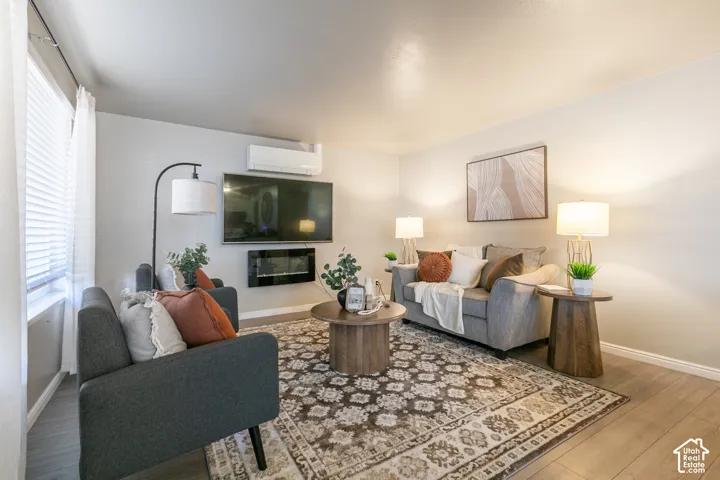 Wood-finish flooring, wall-mounted electric fireplace, and window with privacy blinds