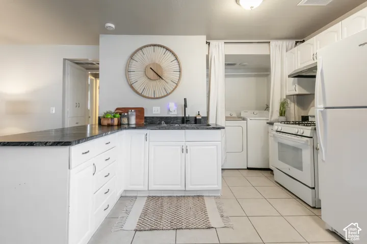 White cabinetry, dark countertops, tile flooring, and a built-in laundry area