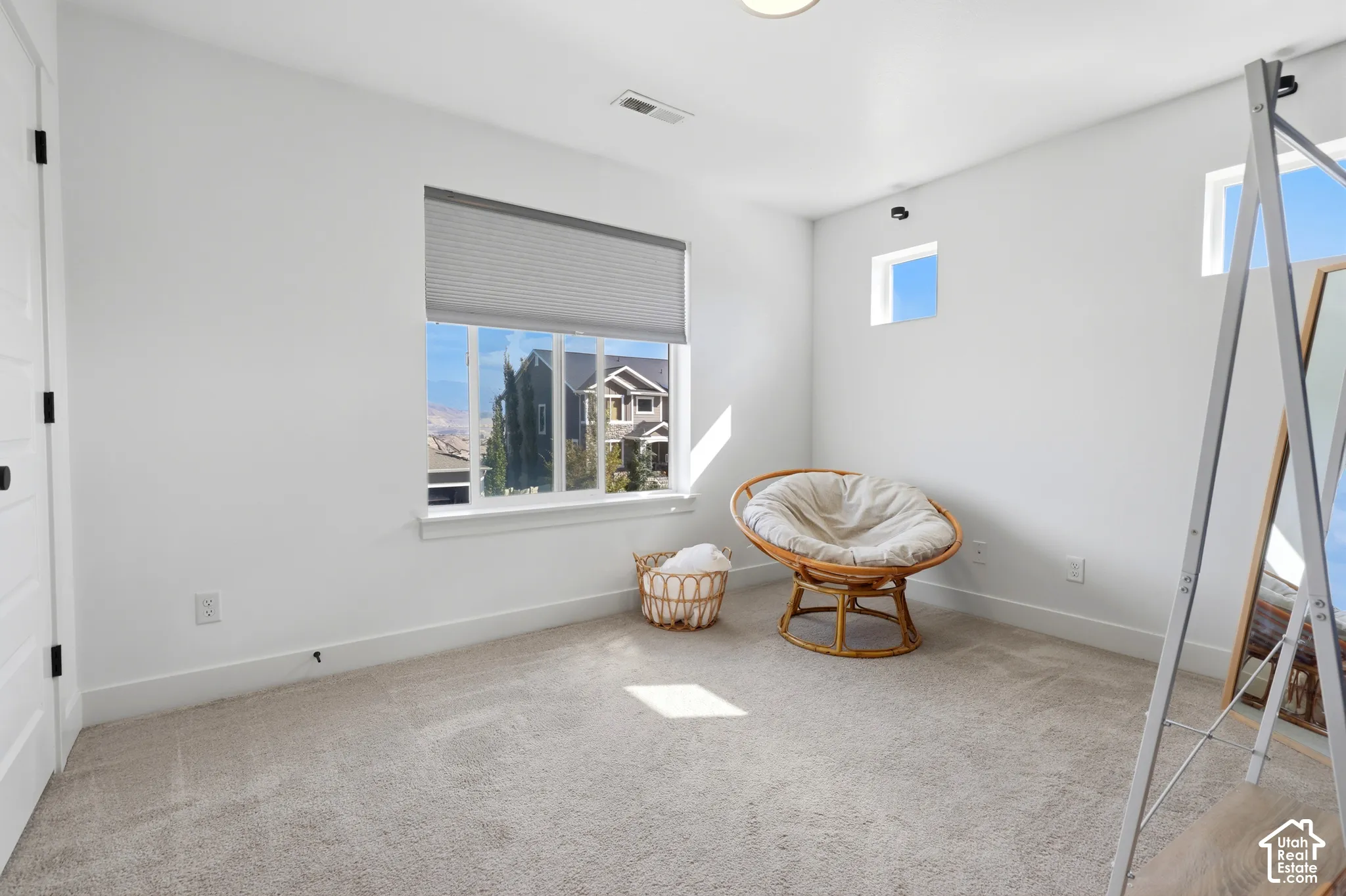 Bright, airy bedroom showcasing abundant natural light from multiple windows, neutral carpet flooring, and clean white walls