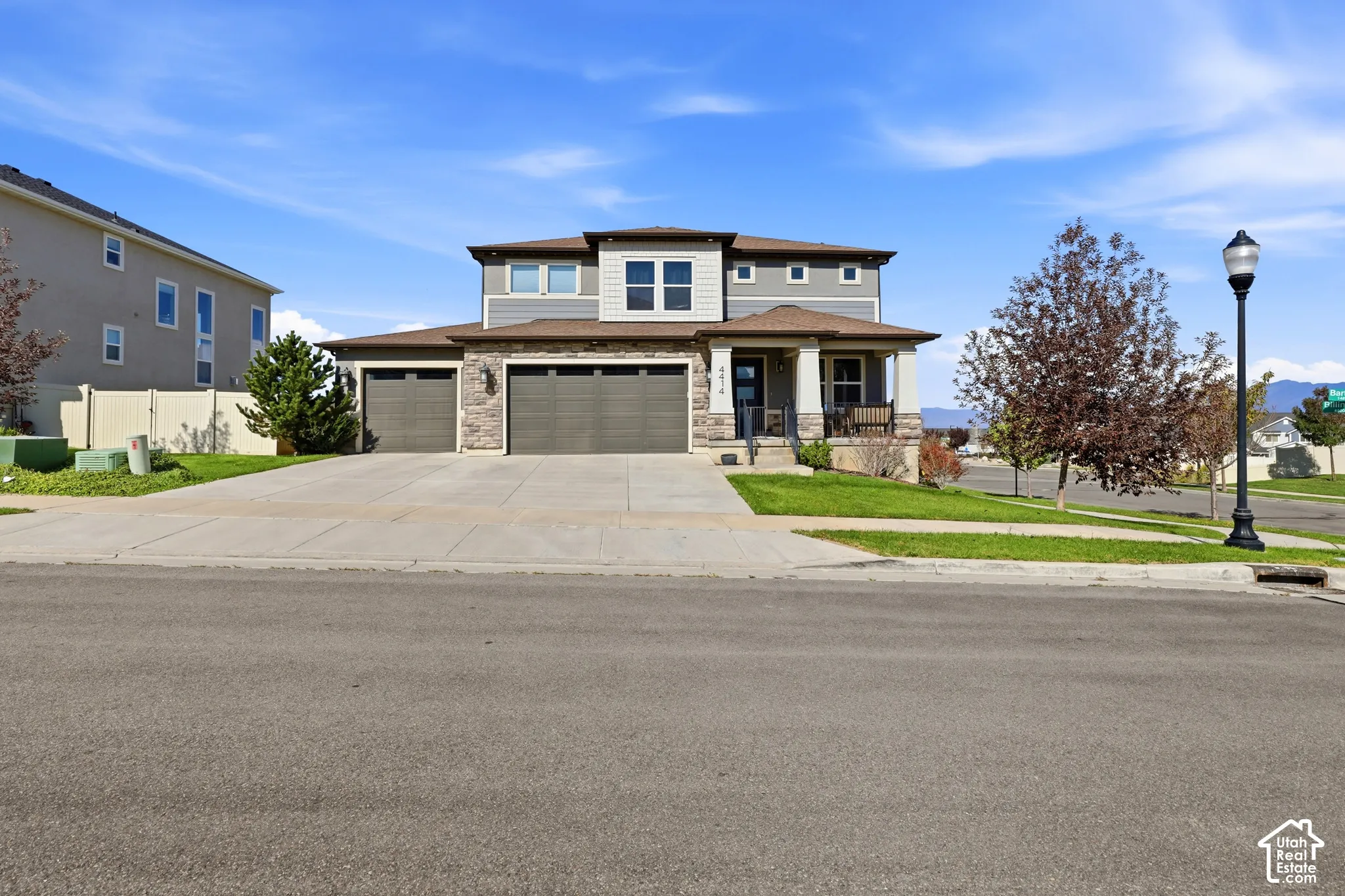 Two-story residence featuring a covered front porch, a multi-car driveway, and a three-car garage with dark wood-finish doors
